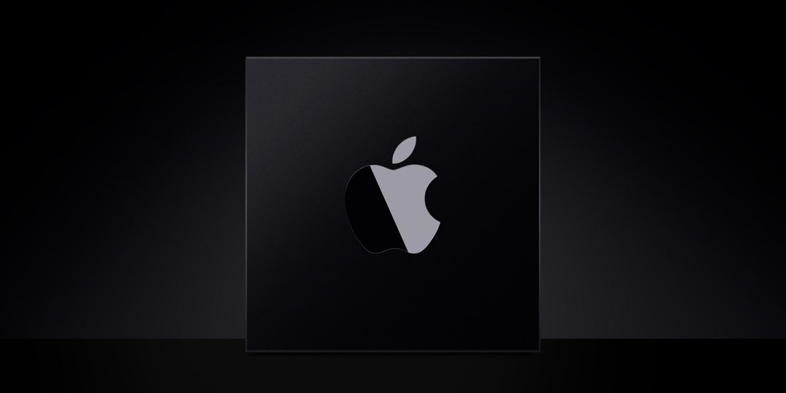 A stylized photo of an Apple M-series chip. It is a matte black square with a shiny Apple logo stamped on it.